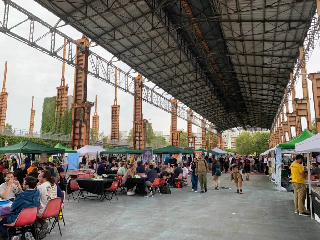 A photo of one end of the TOplay RPG fair, with several bust tents and gaming tables under the canopy.