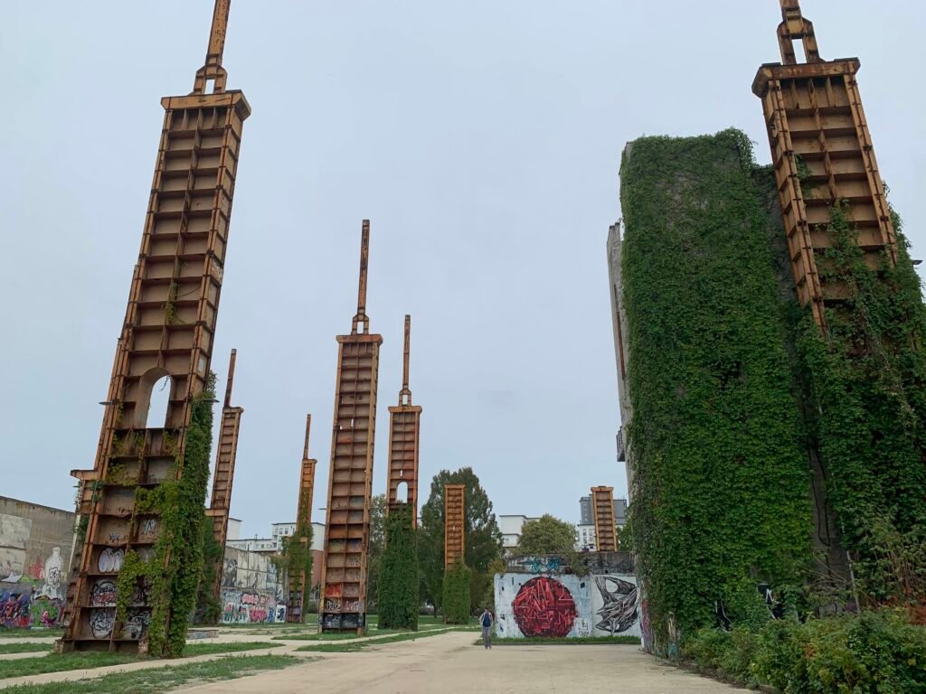 TOplay location. A photo of some of the concrete columns, covered in ivy and graffiti, against an overcast sky.