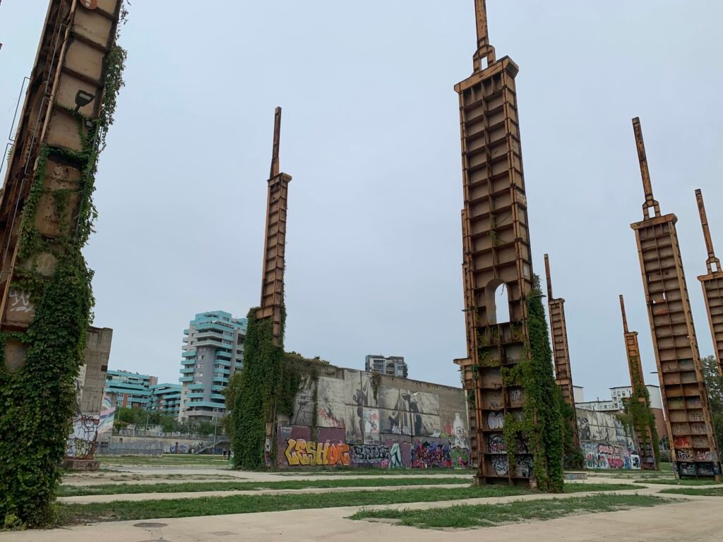 TOplay location. A photo of some of the concrete columns, covered in ivy and graffiti, against an overcast sky.