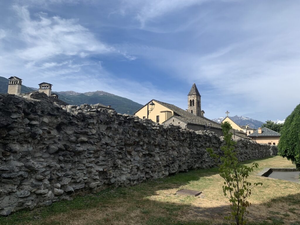 A section of ancient Roman forum wall, with a catholic church in the background.