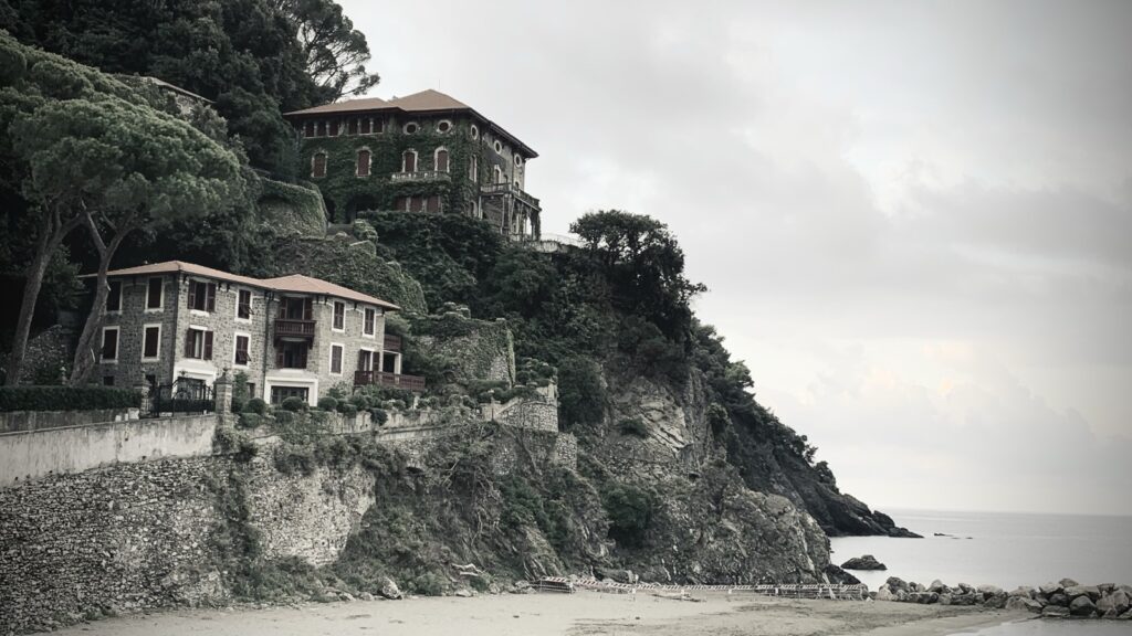 A cluster of villas built along a craggy hillside, overlooking the sea.