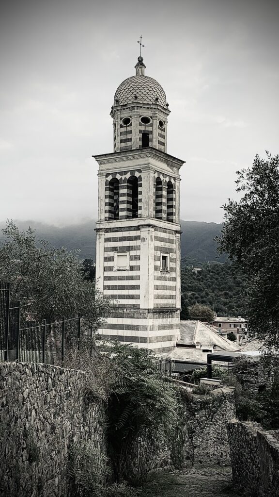 A church clock tower made of black and white marble looms over surrounding trees.