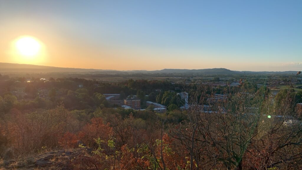 A view from the hilltop of the surrounding hills and plain under the sunrise.